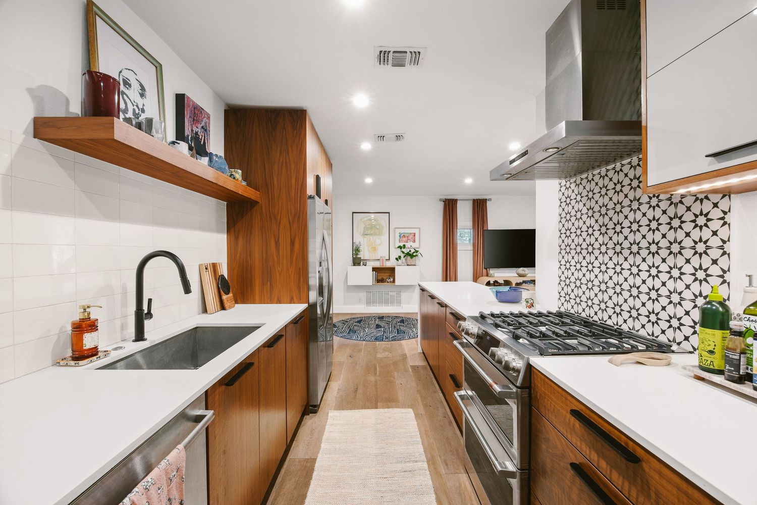 Modern kitchen with walnut cabinets, stainless steel appliances, geometric tile backsplash, and white quartz countertops.