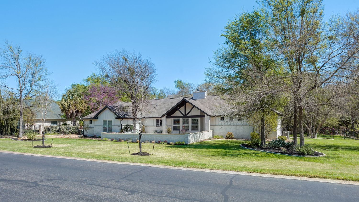 Charming single-story ranch home with lush green lawn, mature trees, and a welcoming facade on a quiet suburban street.