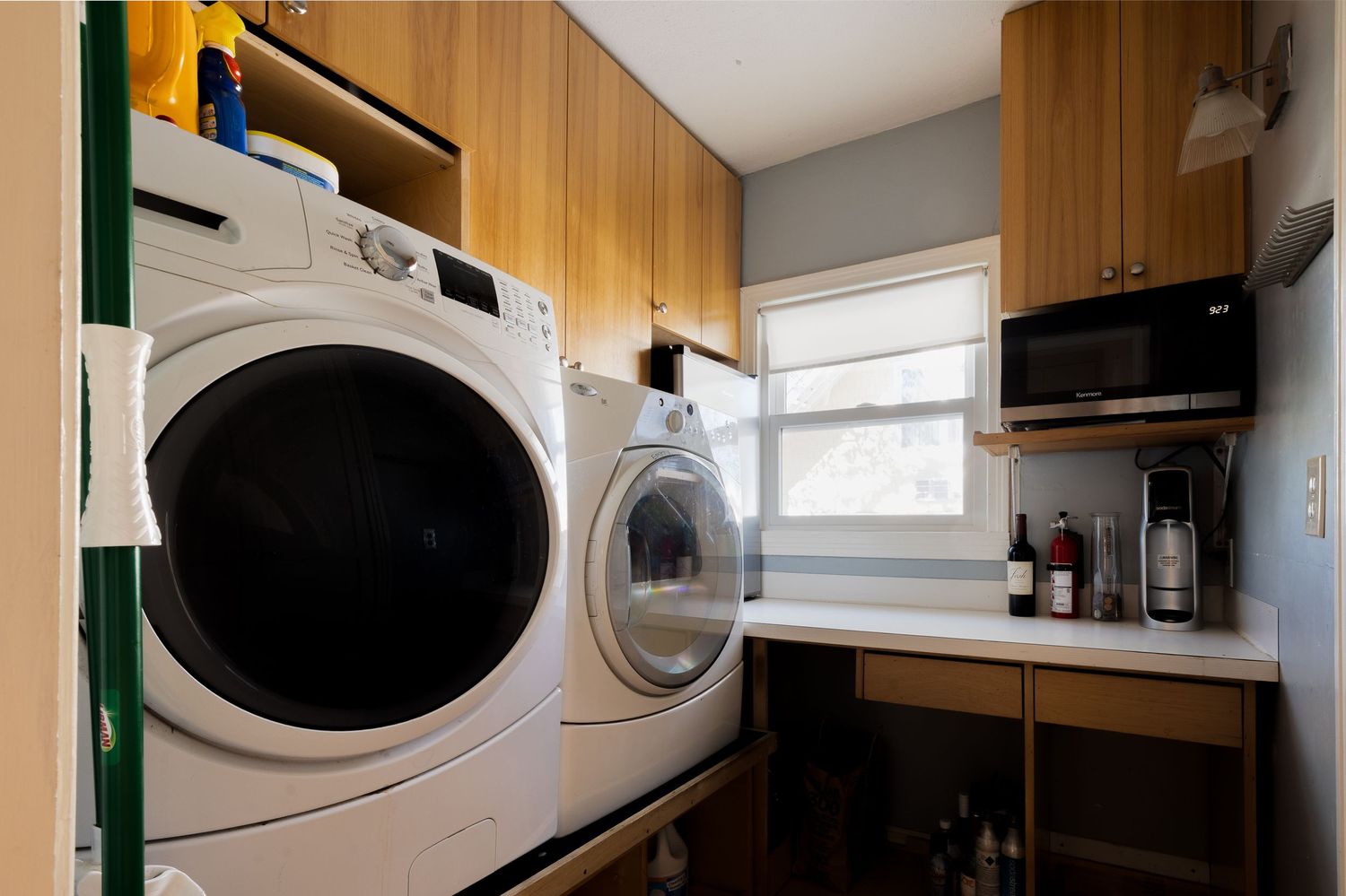 Laundry room with wood cabinets and side-by-side washer dryer units.
