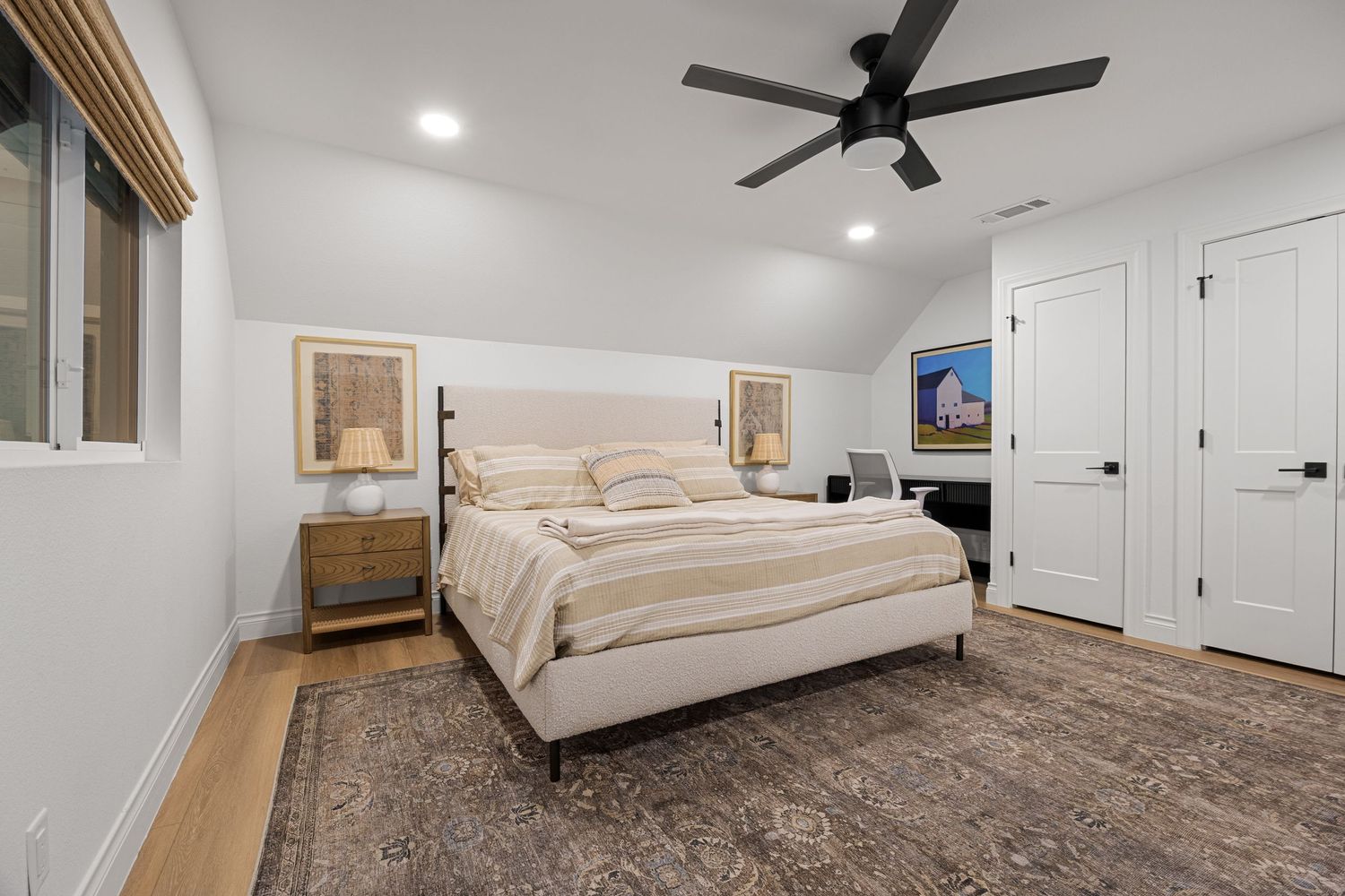 Elegant primary bedroom with upholstered bed, ceiling fan, hardwood floors, and a decorative vintage area rug.