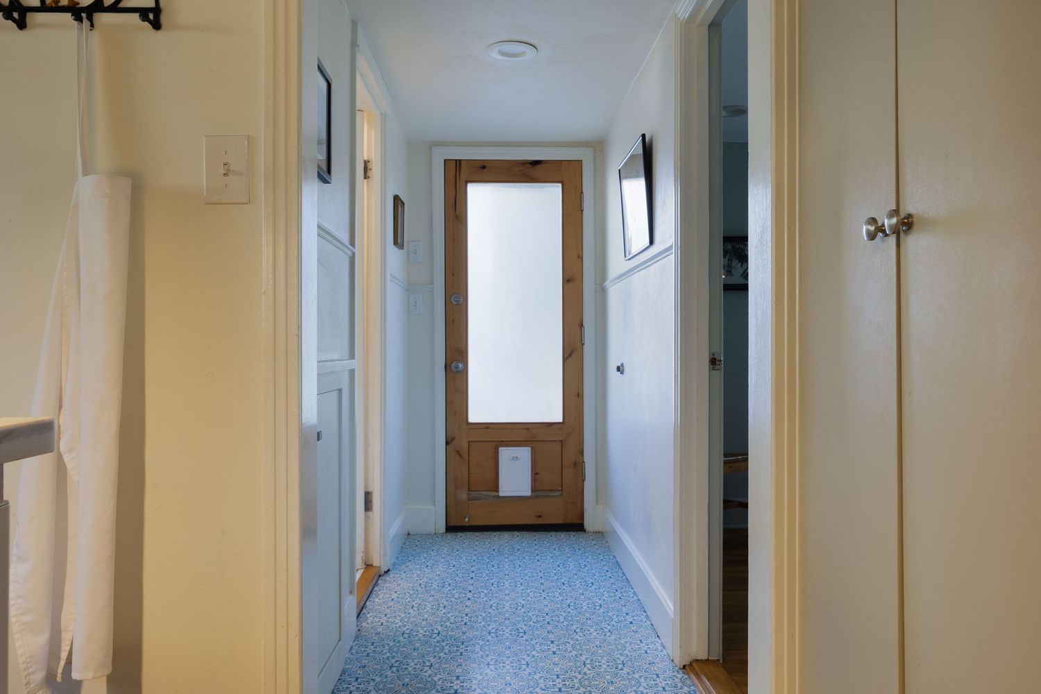 Long hallway with white walls, recessed lighting and wooden flooring.