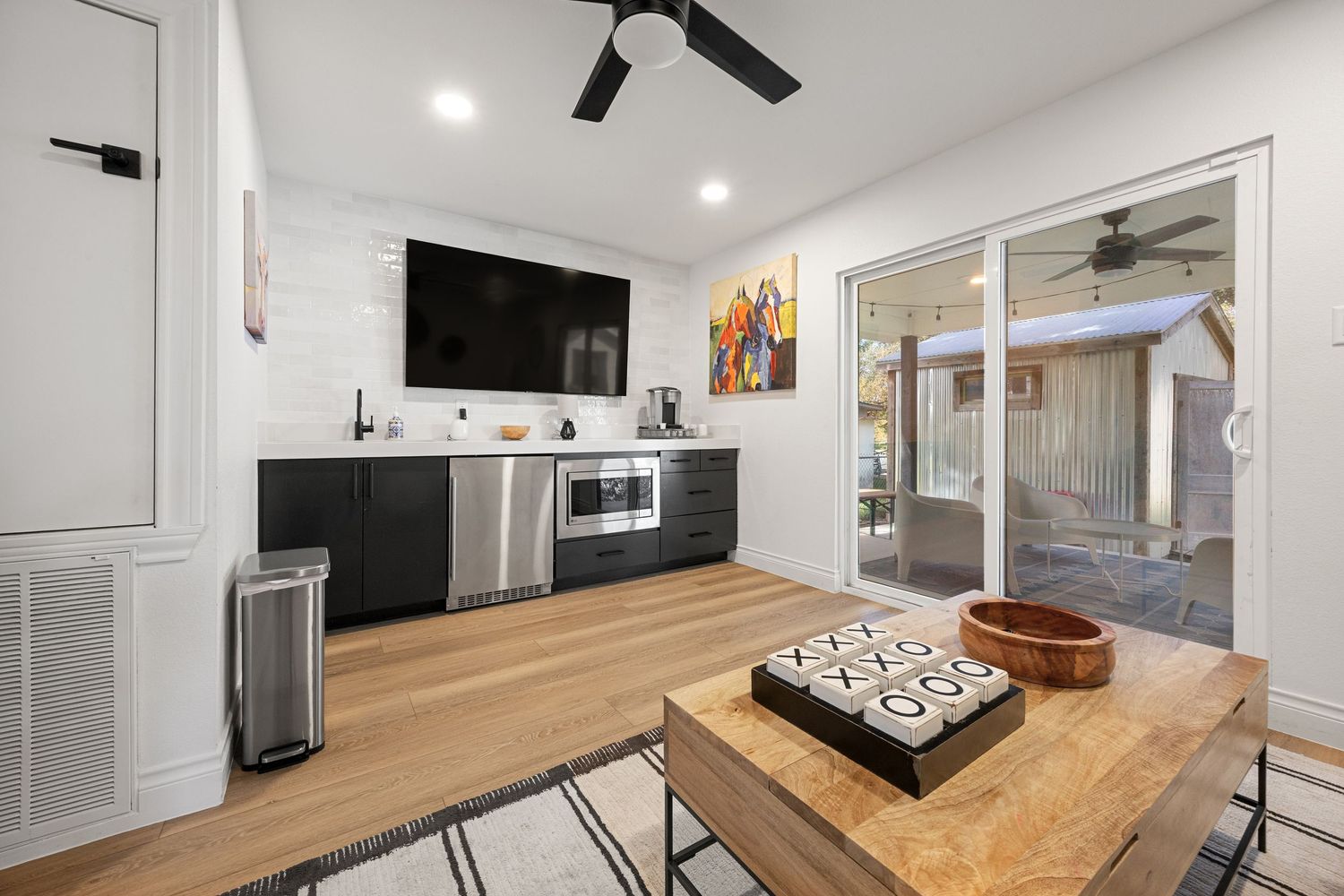 Contemporary kitchenette with black cabinetry, stainless steel appliances, and sliding glass doors to a patio.