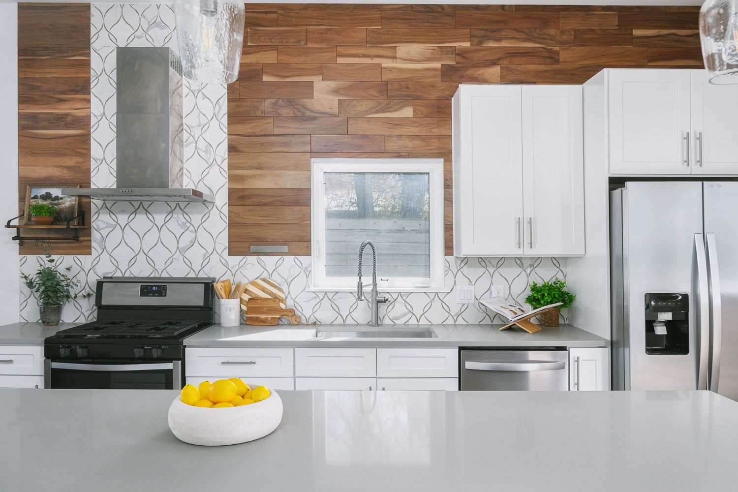 Modern white kitchen with marble backsplash, wood accents, and stainless steel appliances features clean lines and ample storage.