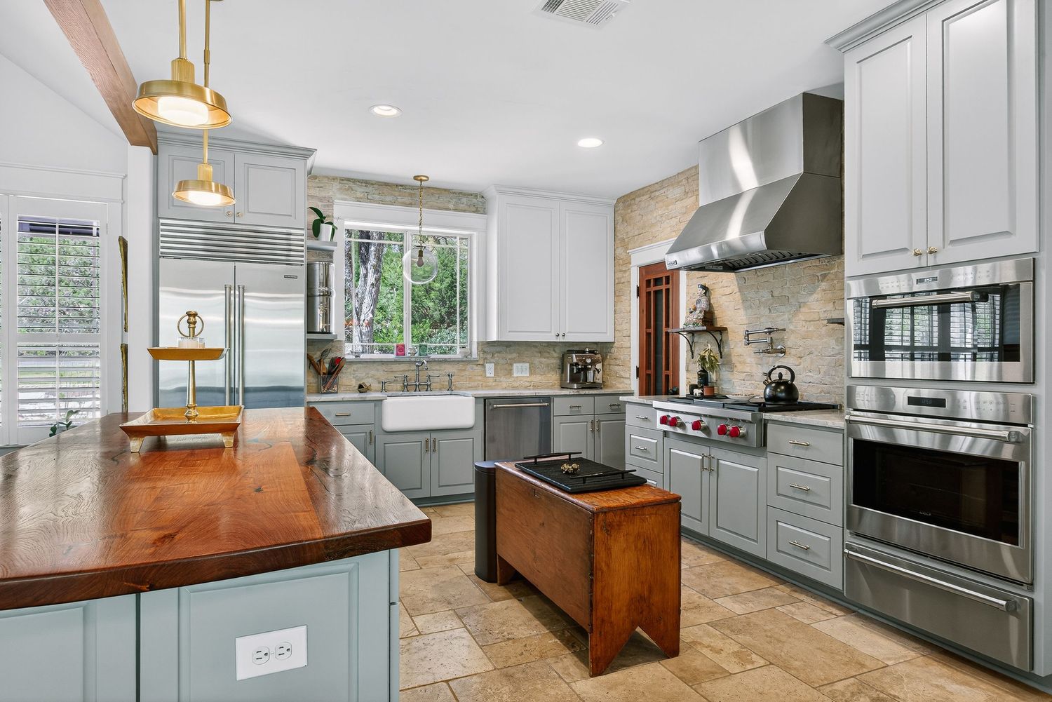 Elegant kitchen with gray cabinets, wood countertops, pendant lights, stainless steel appliances, and a central island.