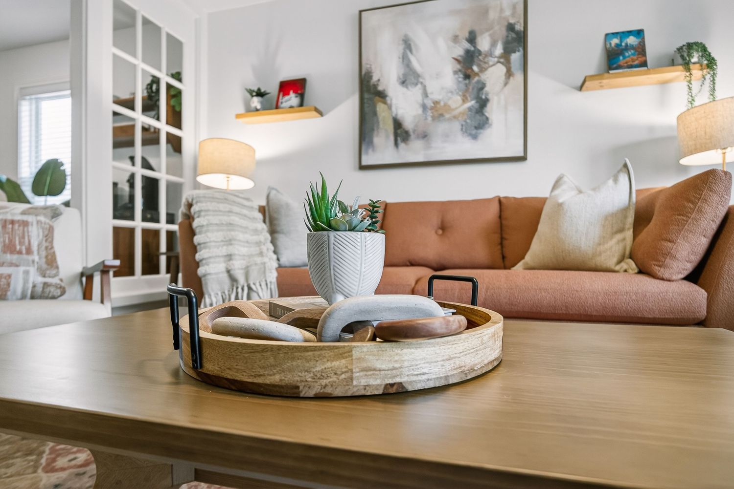 A bright and airy modern living room features white walls, wood furniture, and natural decor elements.