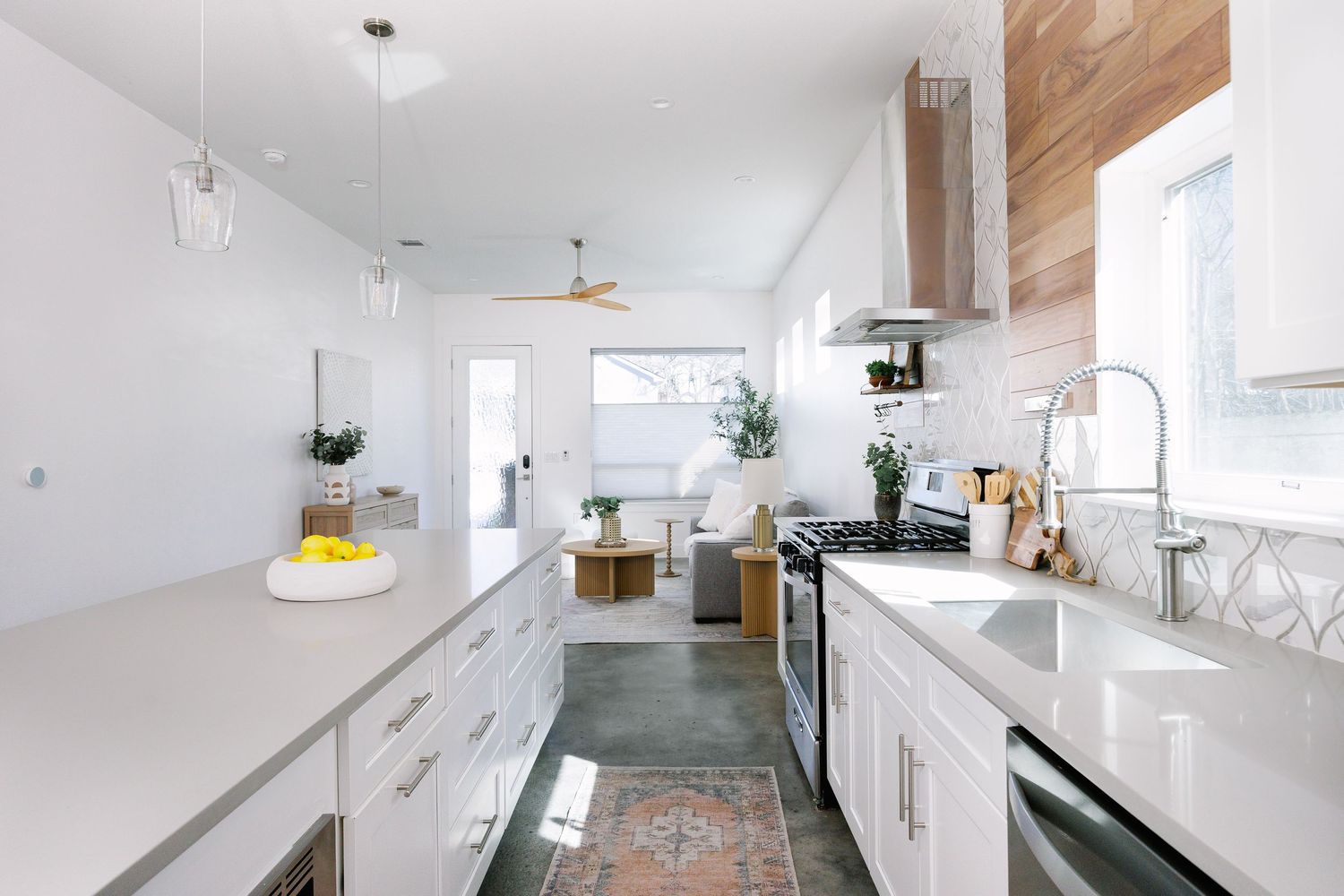 Modern white kitchen interior with wood accents and skylights features sleek cabinets and minimalist design elements.
