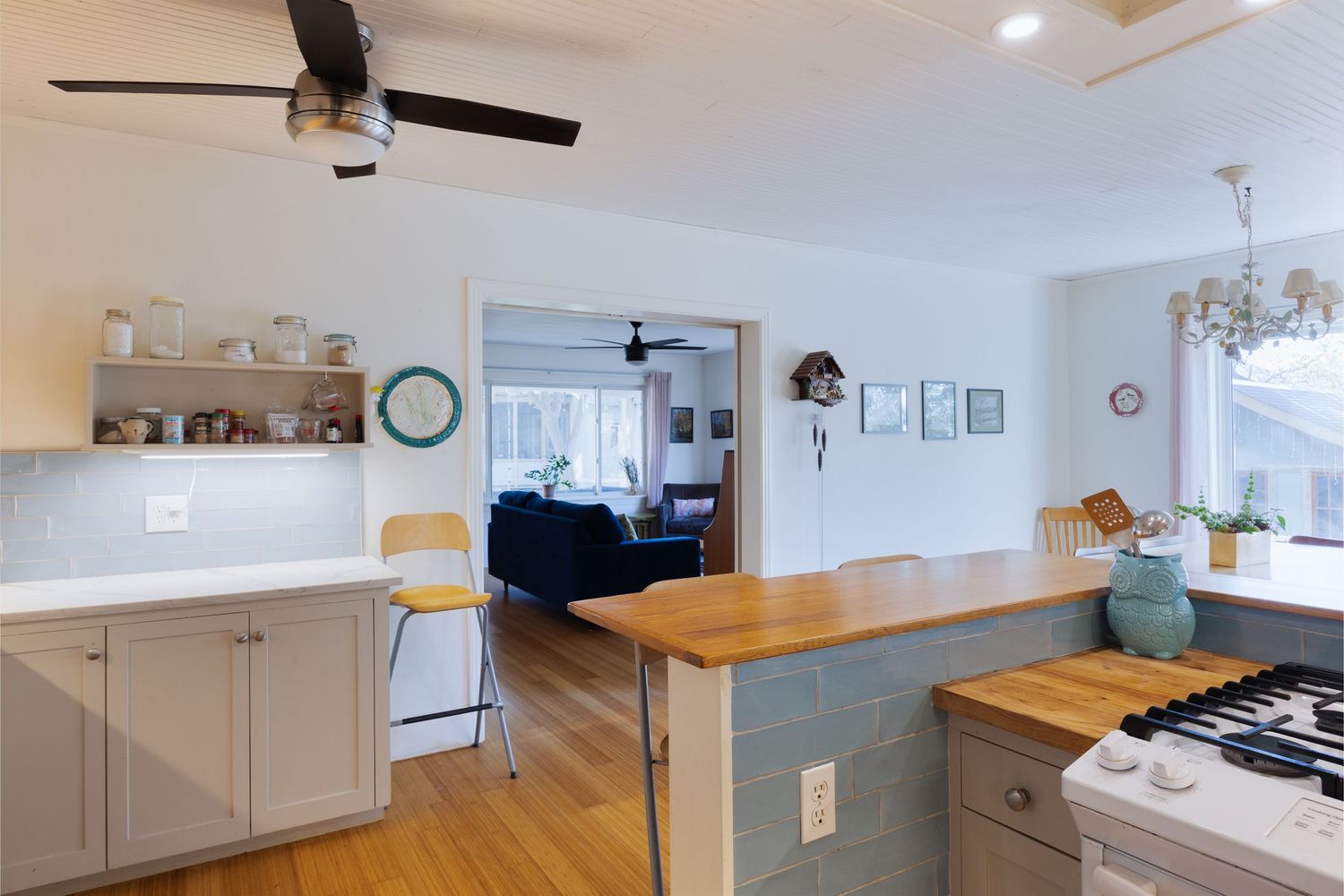 Modern kitchen with white cabinets, butcher block countertops, and recessed lighting.
