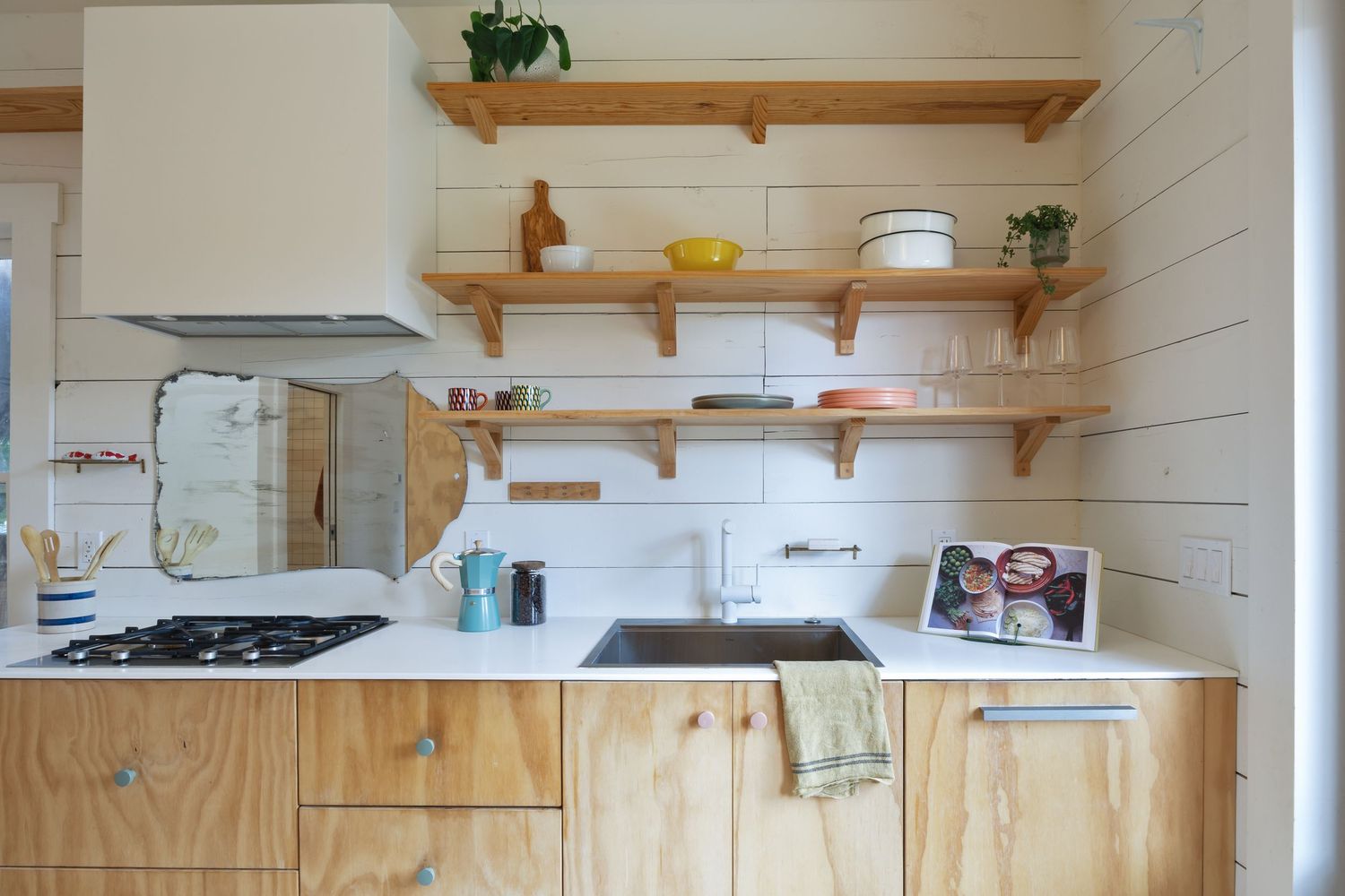 Modern kitchen with plywood cabinets, open shelving, and white shiplap walls.