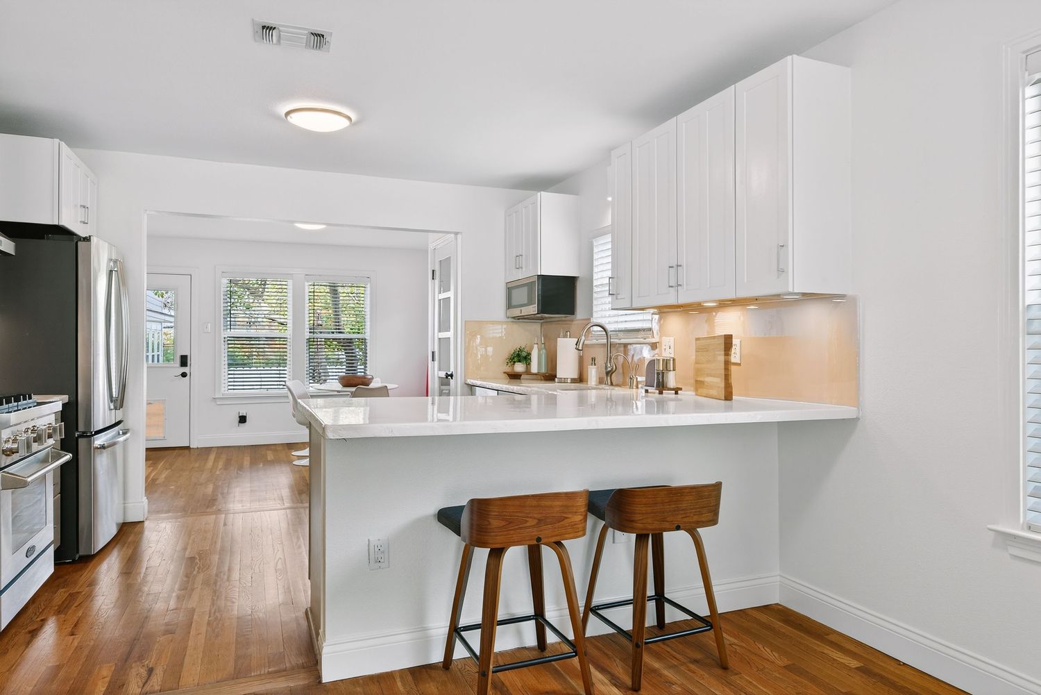 Modern white apartment interior with hardwood floors, recessed lighting and an open concept layout.