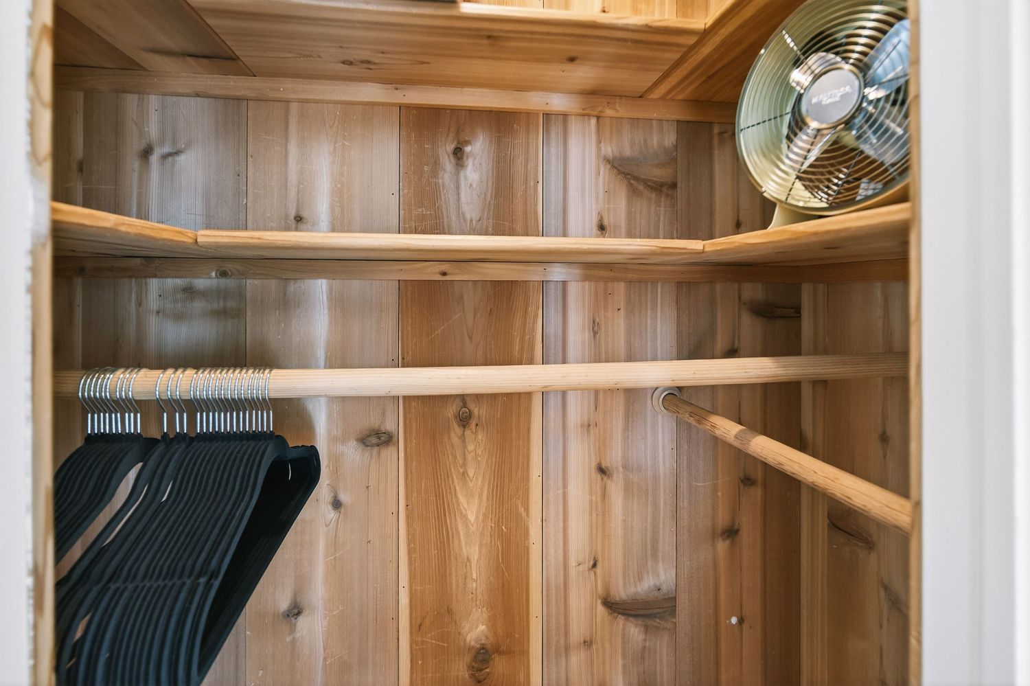 Custom wooden closet organizer with multiple shelves and hanging rods installed in a walk-in closet.