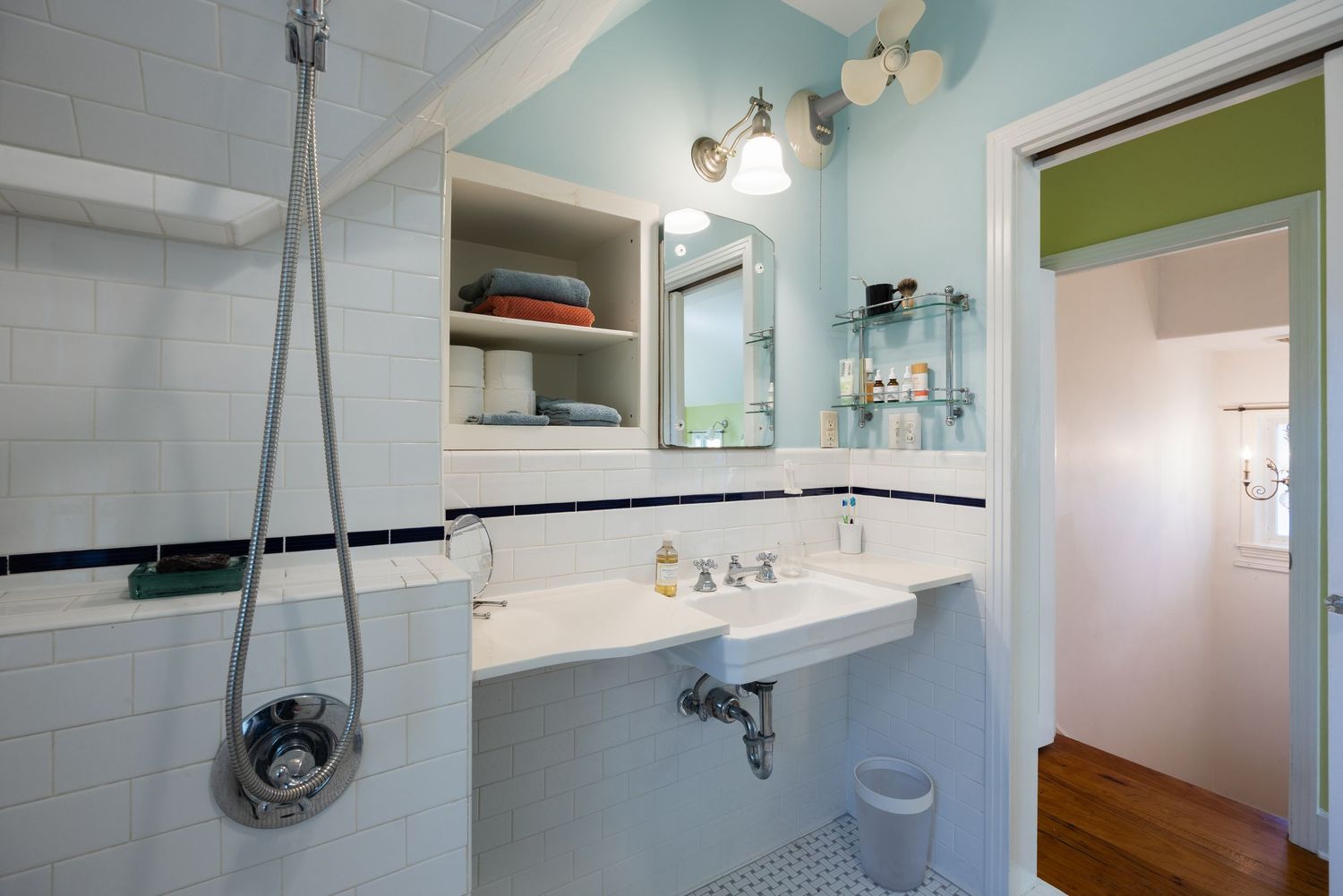 Bright bathroom featuring blue walls, white subway tile, and vintage-style pedestal sink.