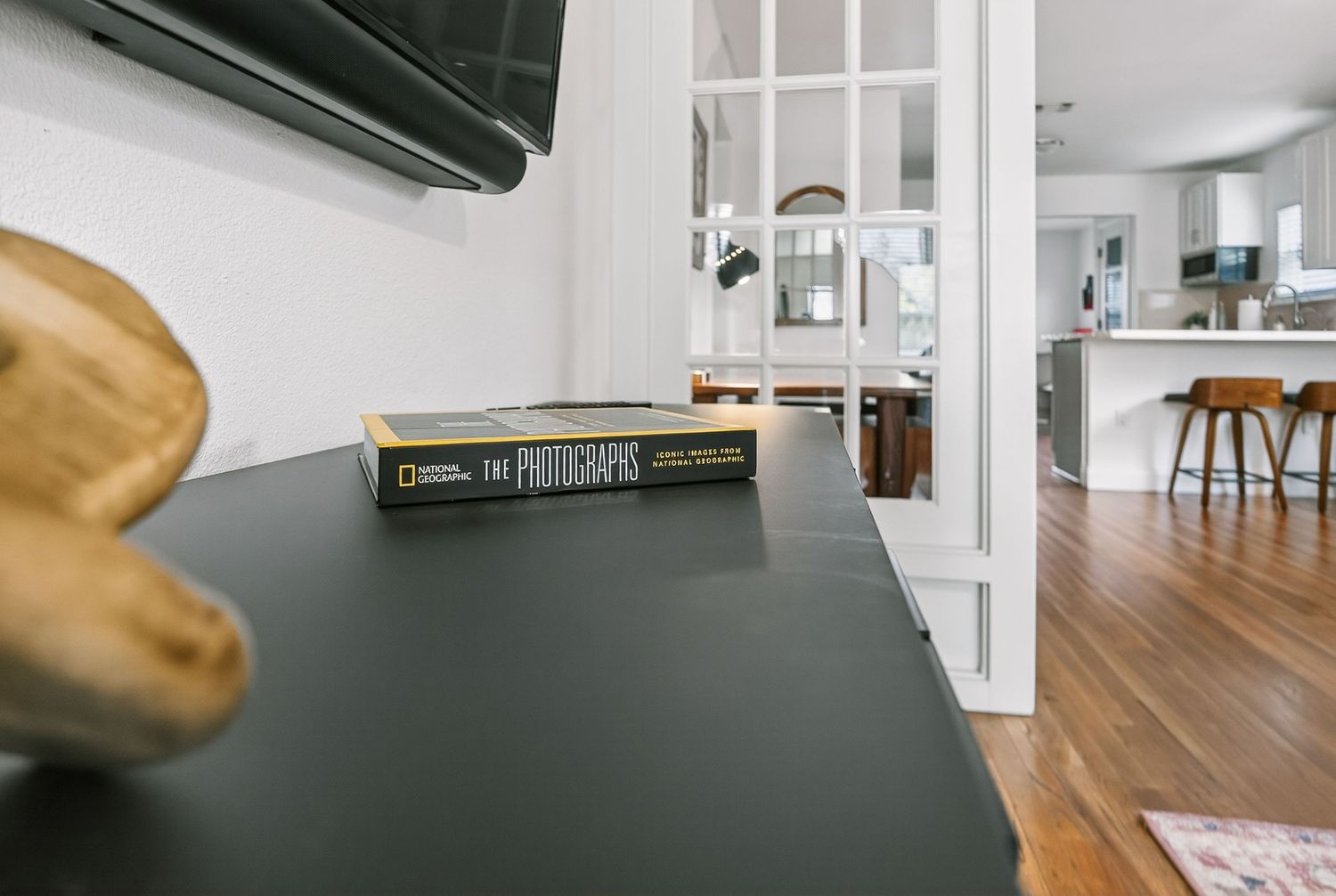 Modern home interior with black desk surface and hardwood floors leading to an open concept kitchen.