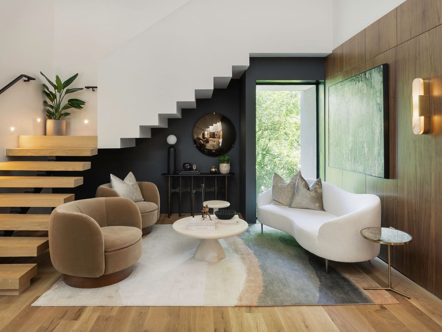 Modern living space with floating staircase, neutral tones, and contemporary furniture.