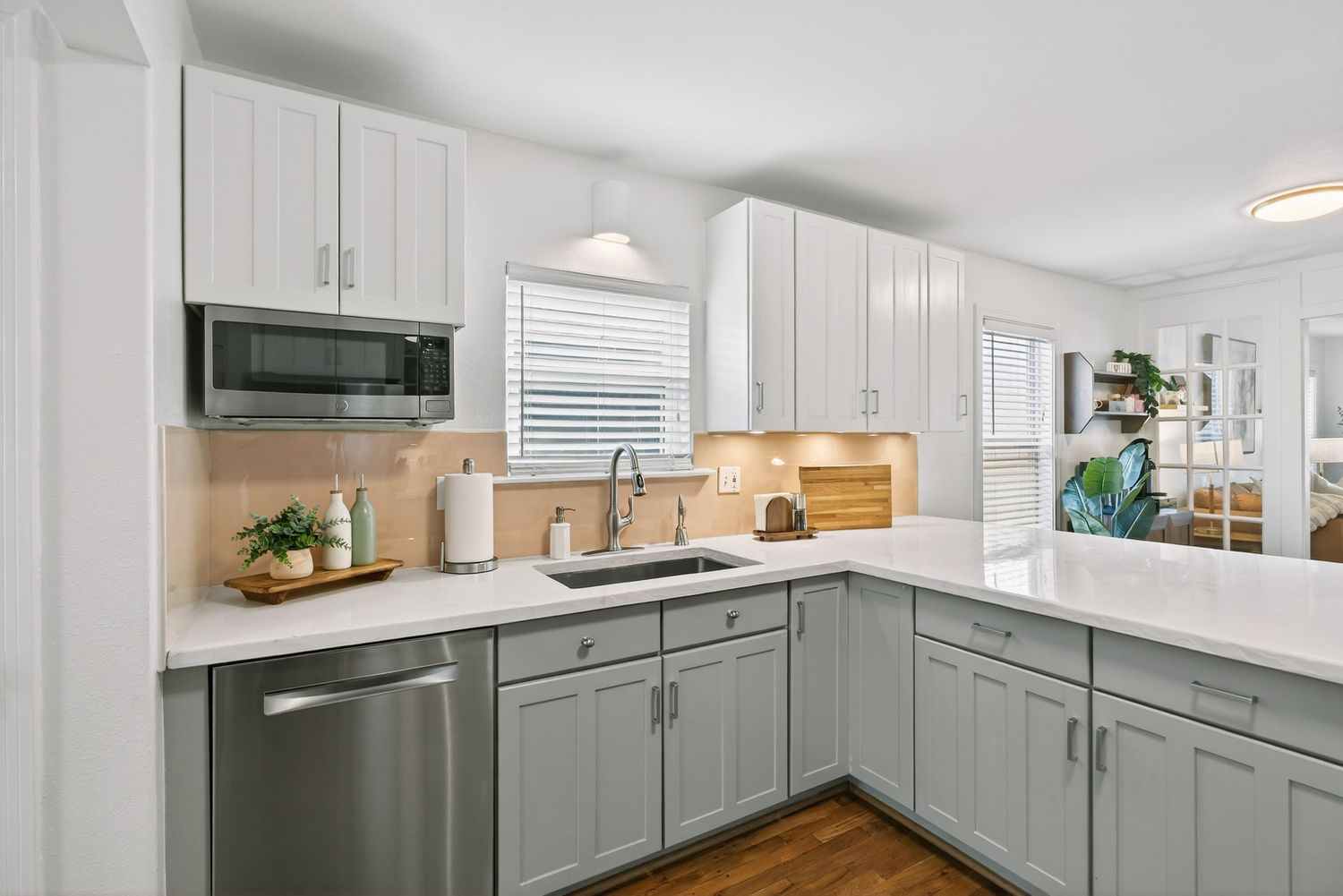 A modern kitchen renovation showcases white cabinets, gray accents, and stainless steel appliances in a bright space.