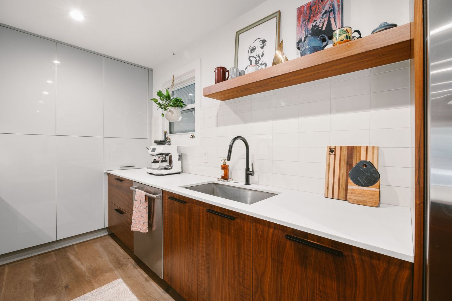 Modern kitchen with walnut cabinets, white quartz countertops, stainless steel sink, and open shelving with decor.
