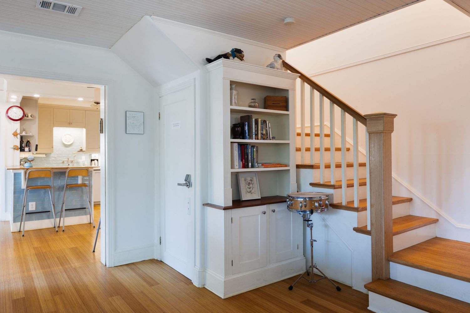 Bright hallway with white walls, wooden stairs and built-in storage cabinets.