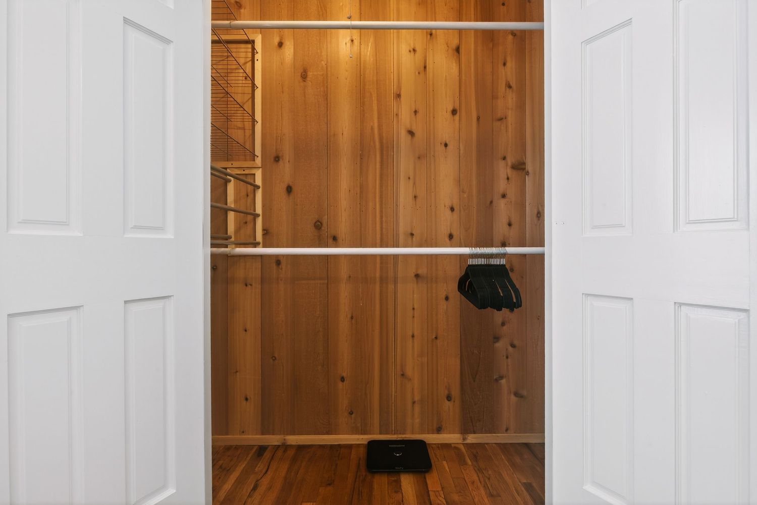 Wood paneled walls and white doors create a rustic interior hallway with contrasting textures and finishes.