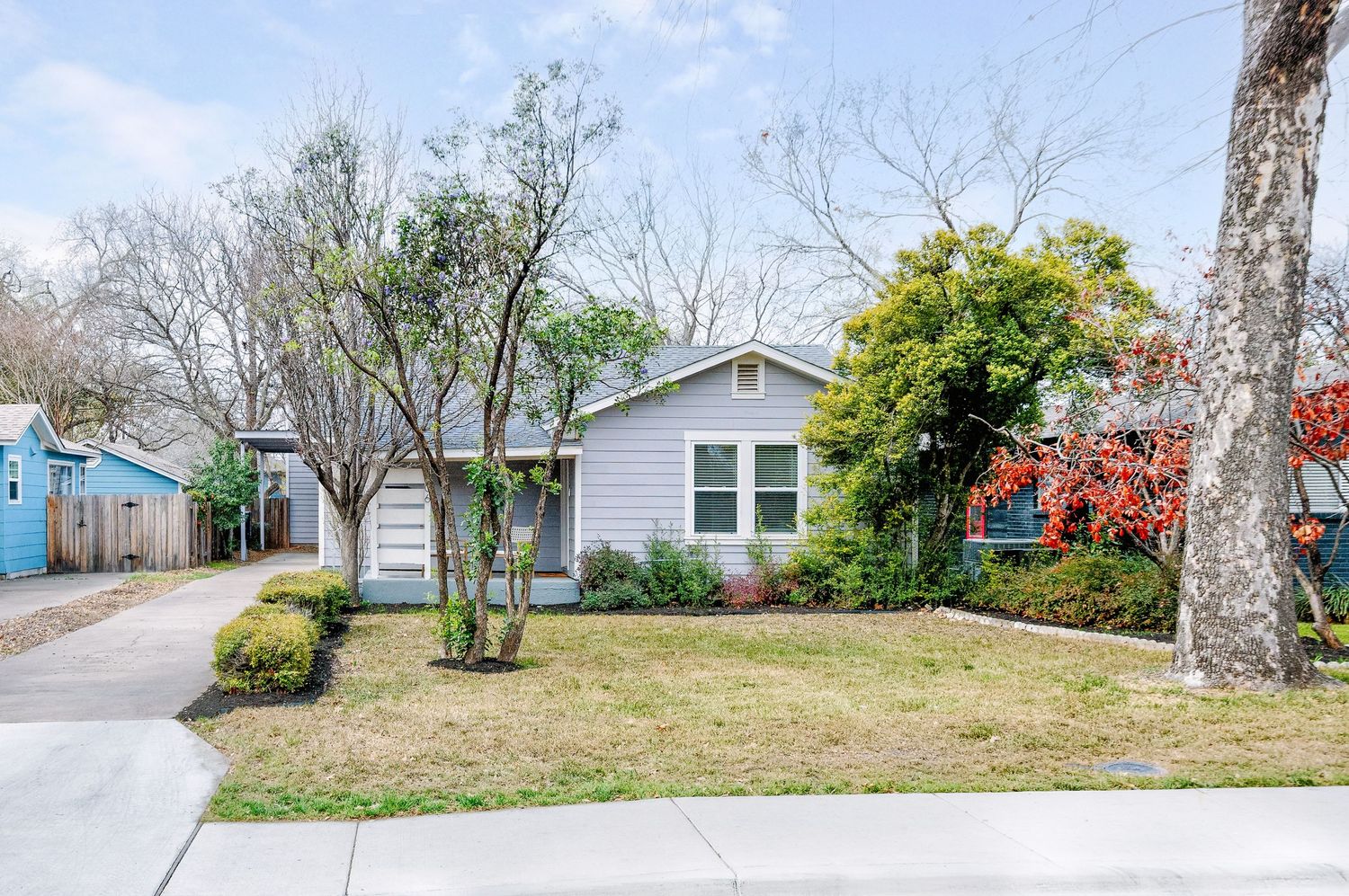A panoramic view of a residential neighborhood with houses, trees, and landscaping along a curved suburban street.