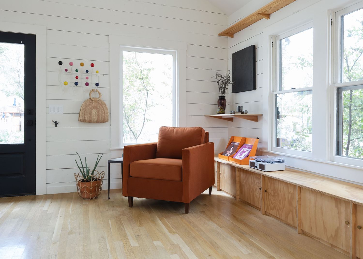 Airy living room with white shiplap walls, wooden beams, and leather accent chair.