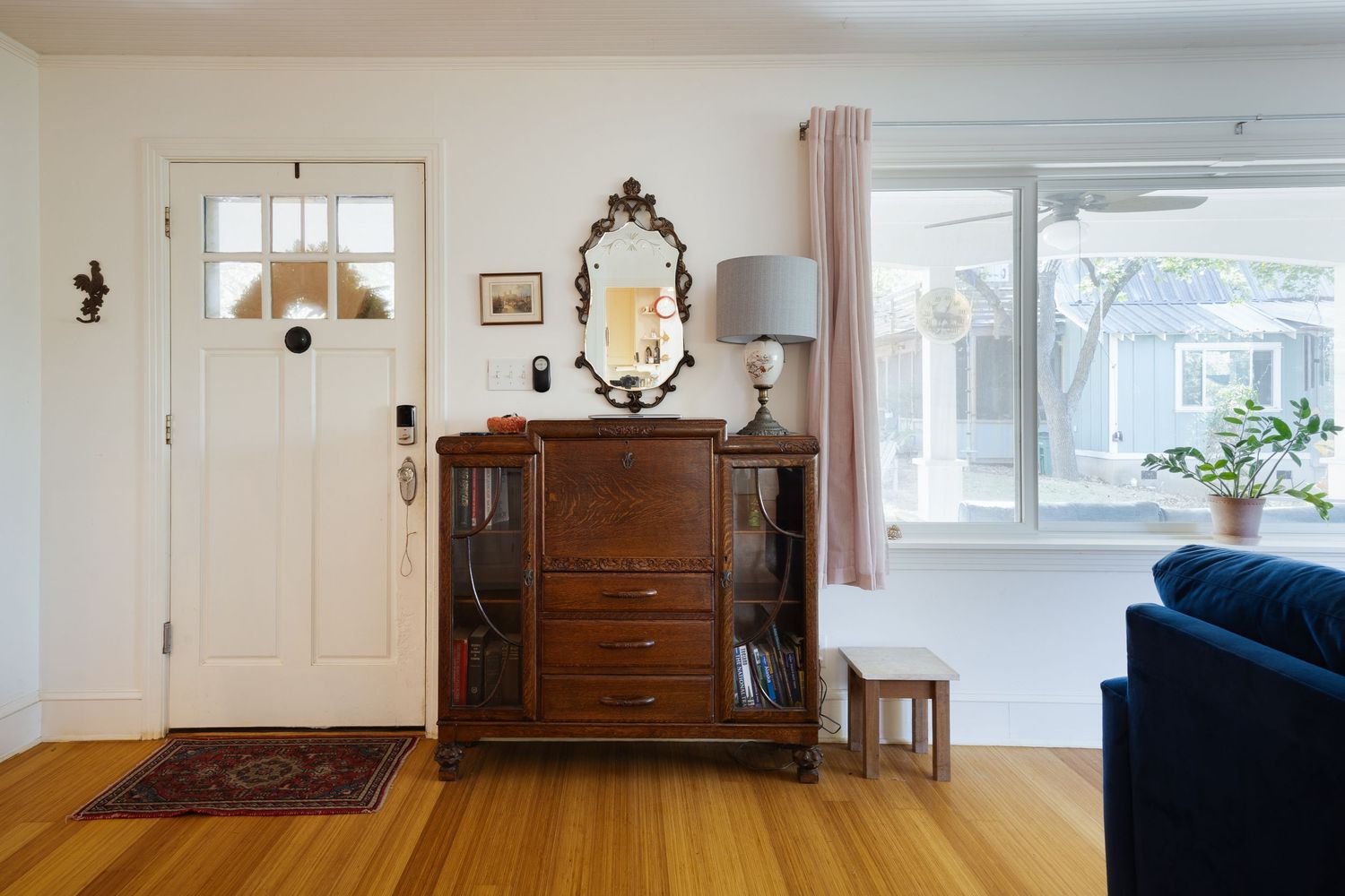 Open floor plan interior with antique furniture and blue sofa against white walls.
