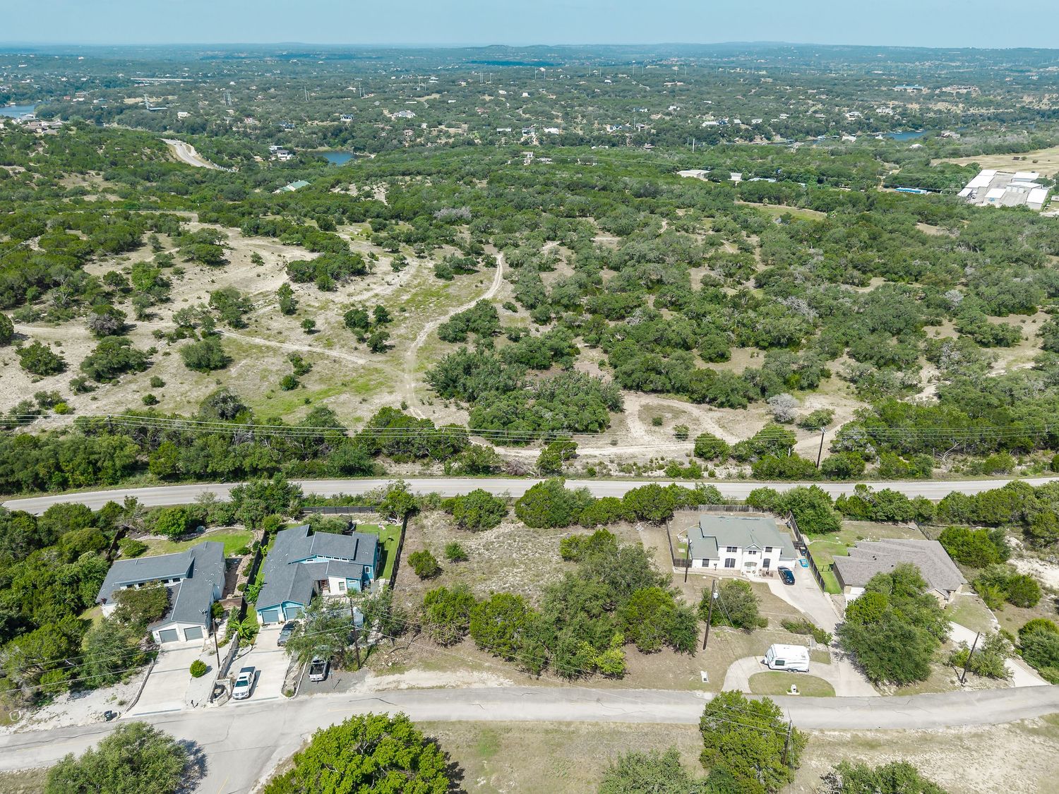 Aerial view of luxury homes nestled among dense trees in a sprawling Texas Hill Country residential neighborhood.