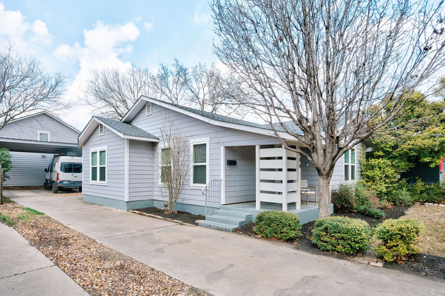 Exterior view of modern gray house with white trim and landscaping showing multiple angles of the property.