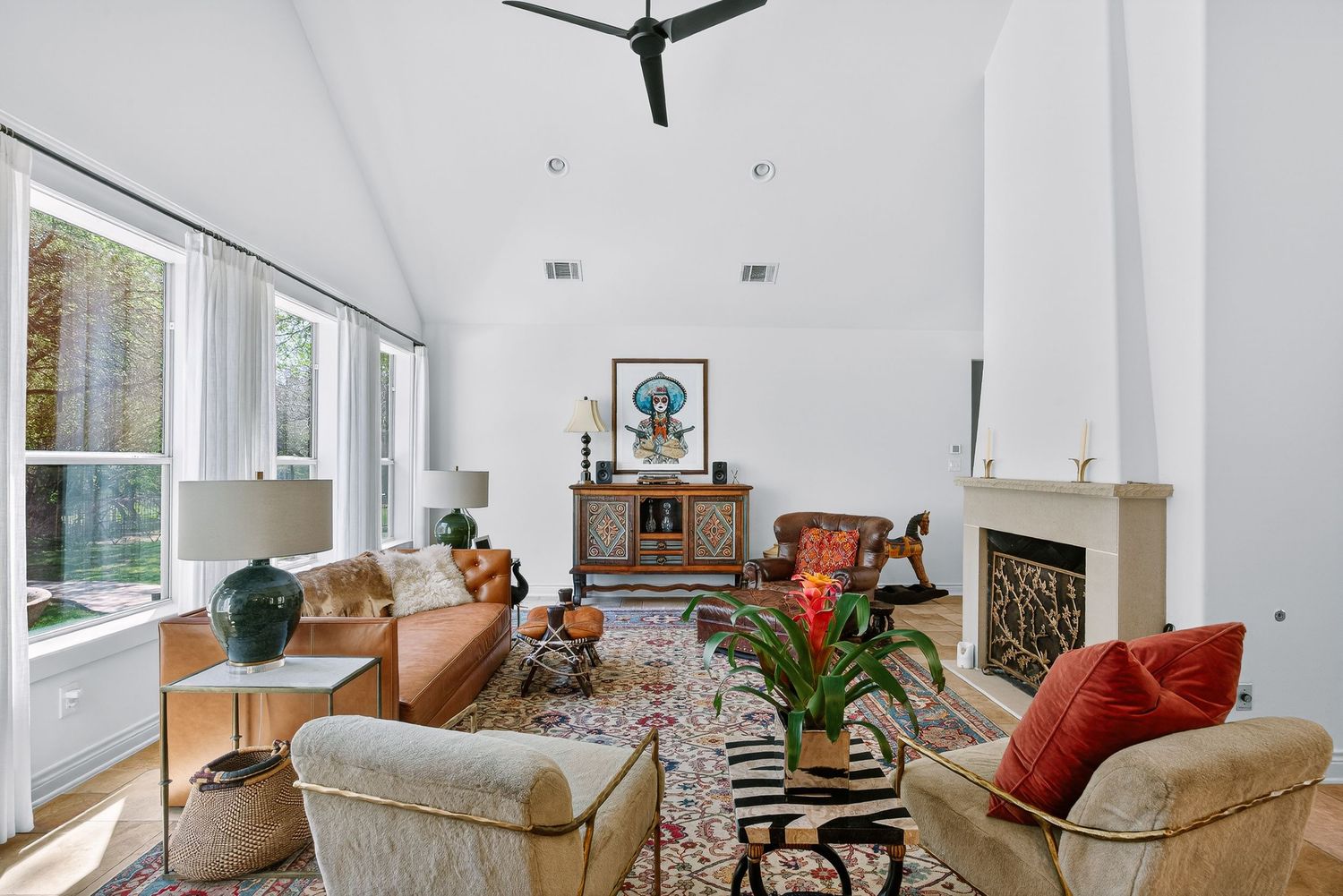 Modern open concept living room features white walls, beige furniture, and orange accent pillows with natural light.