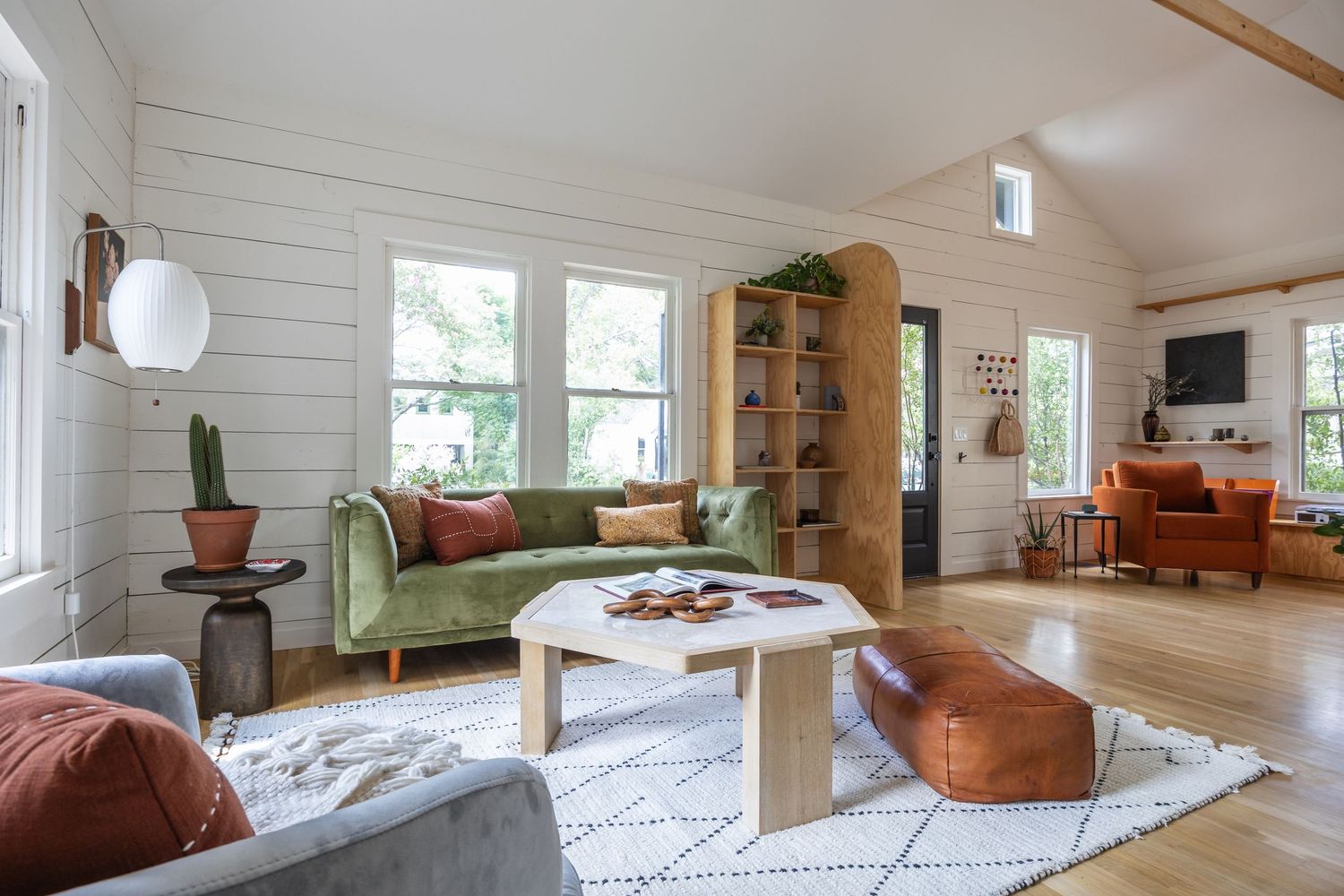 Minimalist living area featuring white walls, wood beams, and mid-century modern furniture.