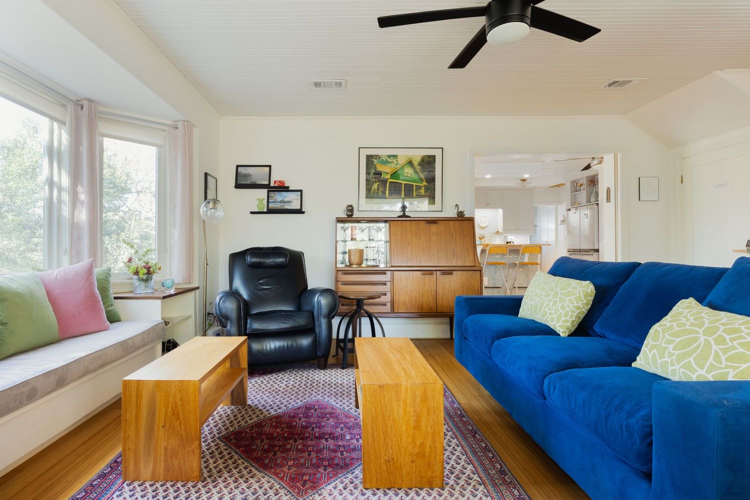 Living room with blue sofa, hardwood floors, and large windows providing natural light.