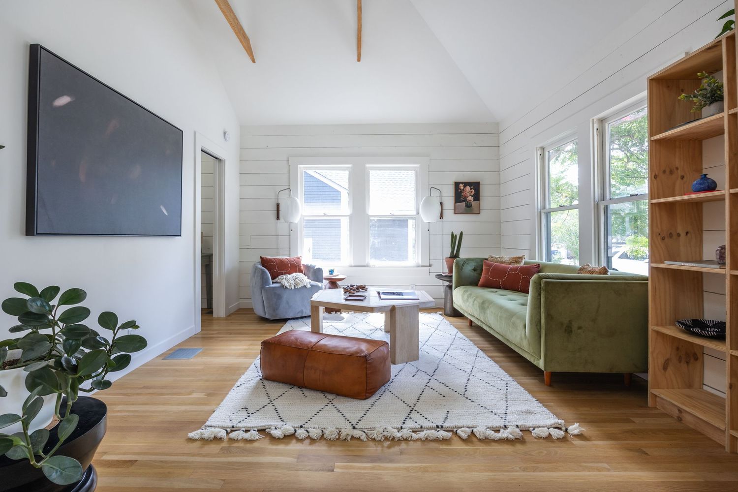 Open concept living space with white shiplap walls, wooden accents, and modern furnishings.