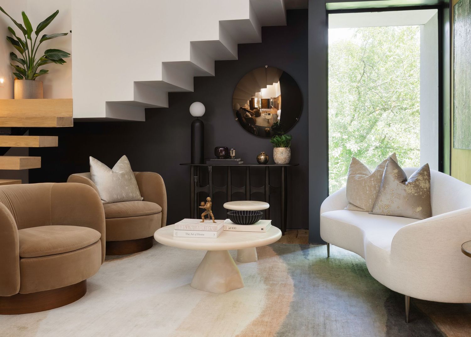 Minimalist living space with curved furniture, floating stairs, and large windows overlooking greenery.