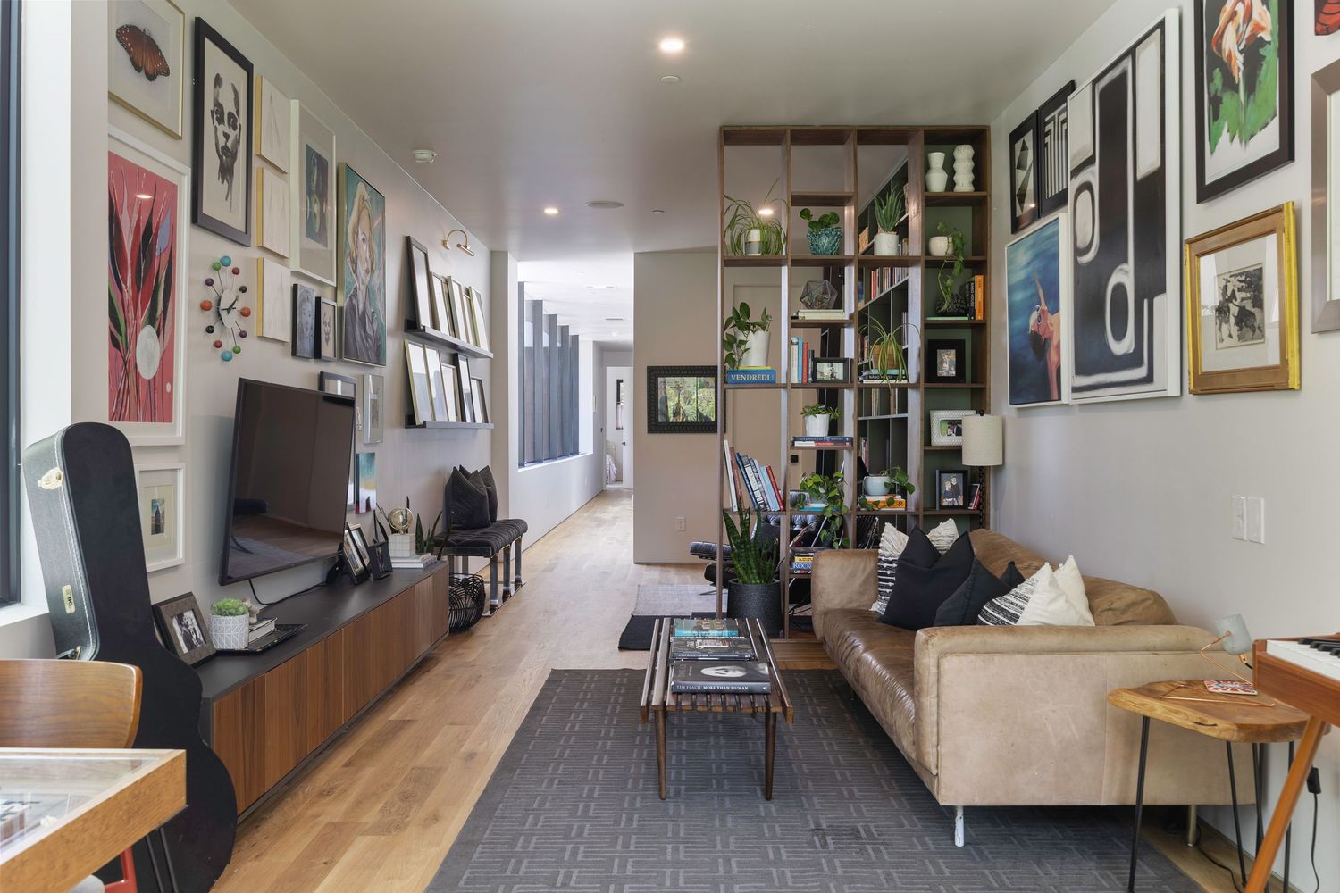 Long hallway with white walls decorated with framed artwork and photographs.
