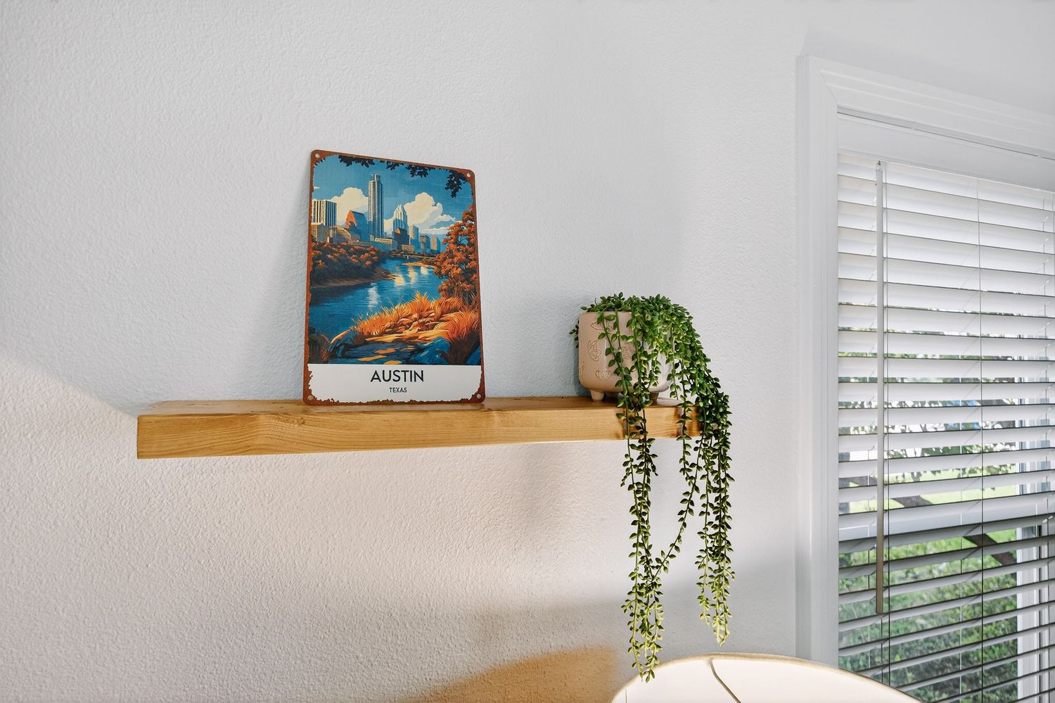 Decorative floating wooden shelf with a vintage movie poster and trailing plant against a white wall.