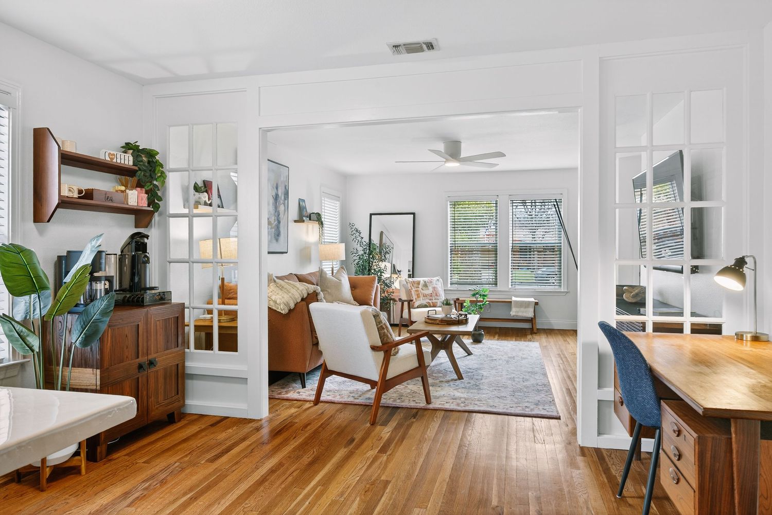 Modern open concept apartment interior with white walls, hardwood floors, and natural light streaming through windows.