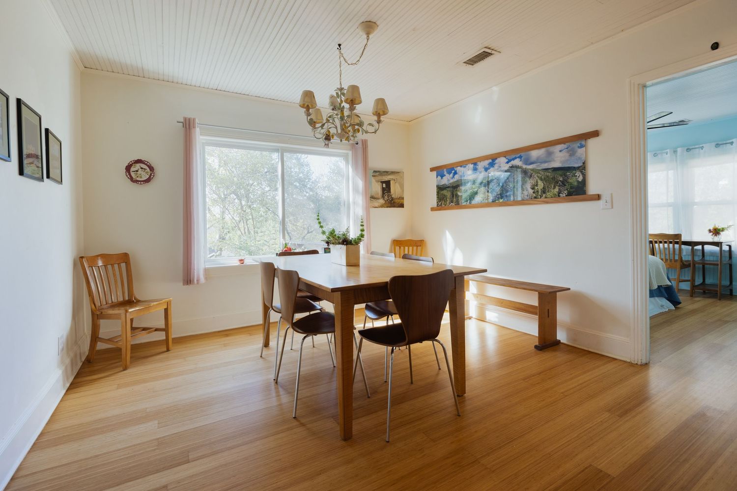 Open concept dining and living space with hardwood flooring and beadboard ceiling.