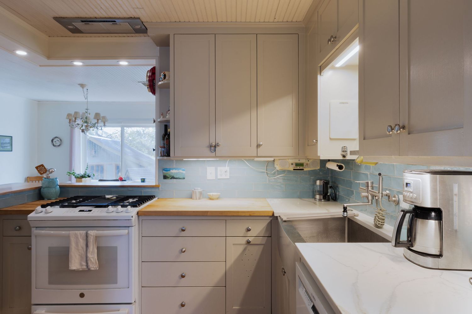 Long view of kitchen showing white cabinets and beadboard ceiling details.