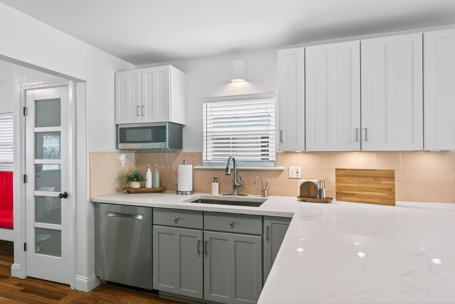 Modern two-tone kitchen features white upper cabinets, gray lower cabinets, quartz countertops and wood accents.