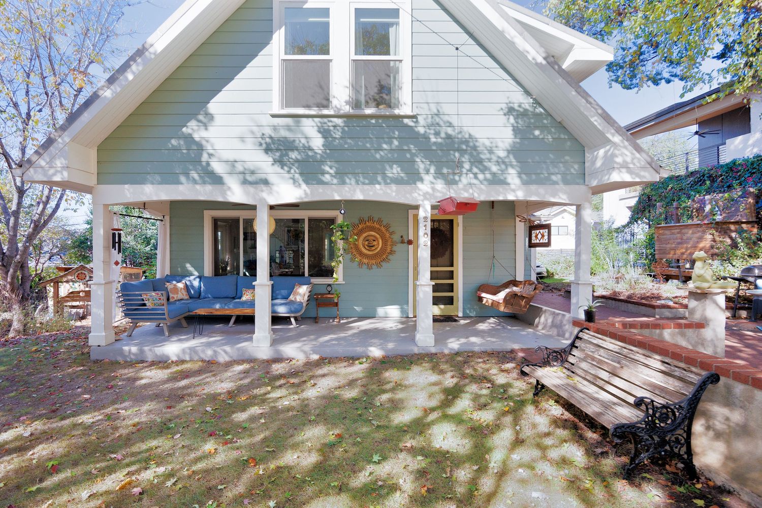 Side view of house exterior with covered porch and landscaped yard.