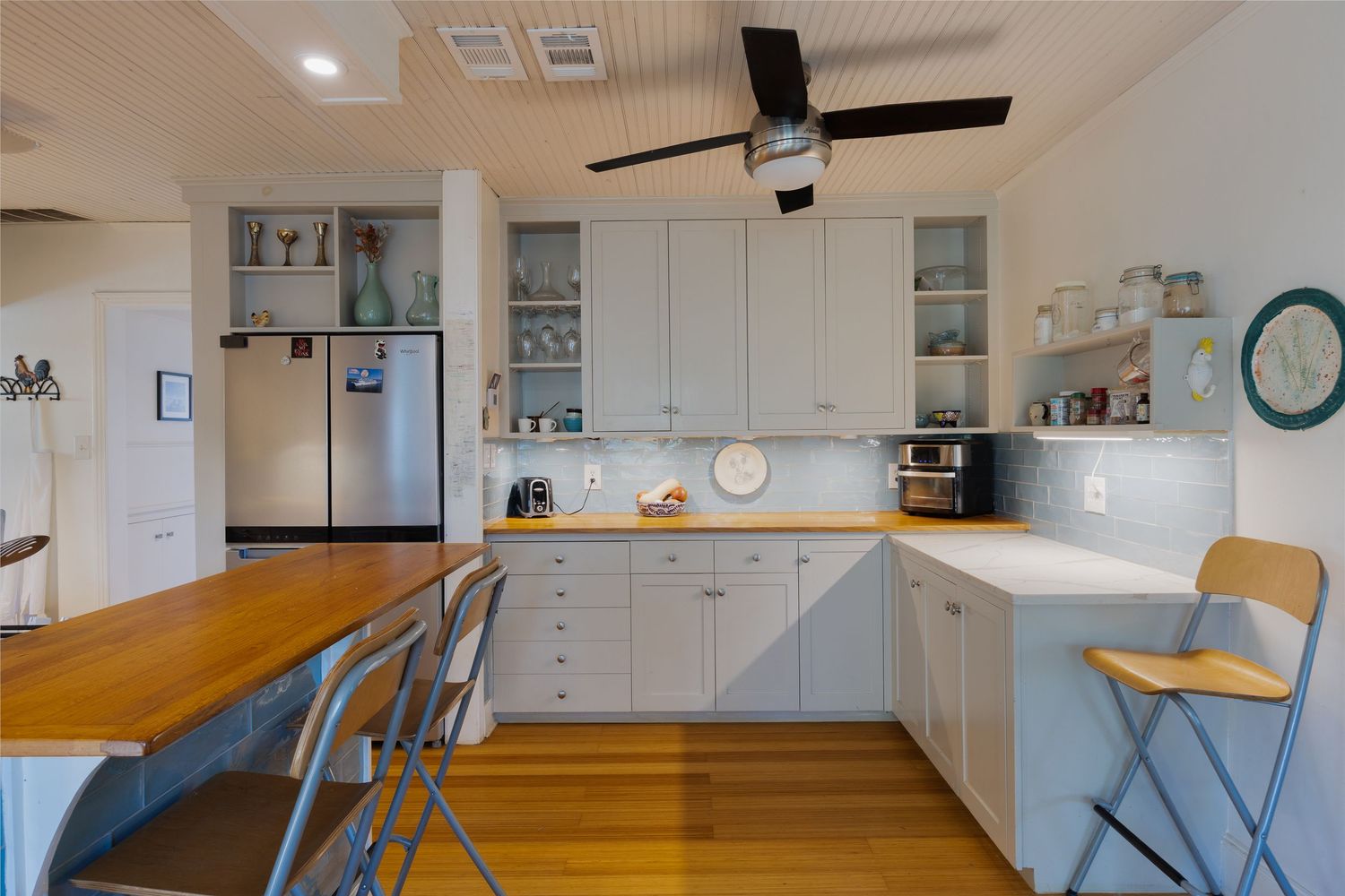 Modern kitchen with white cabinets and wood countertops in an open floor plan.