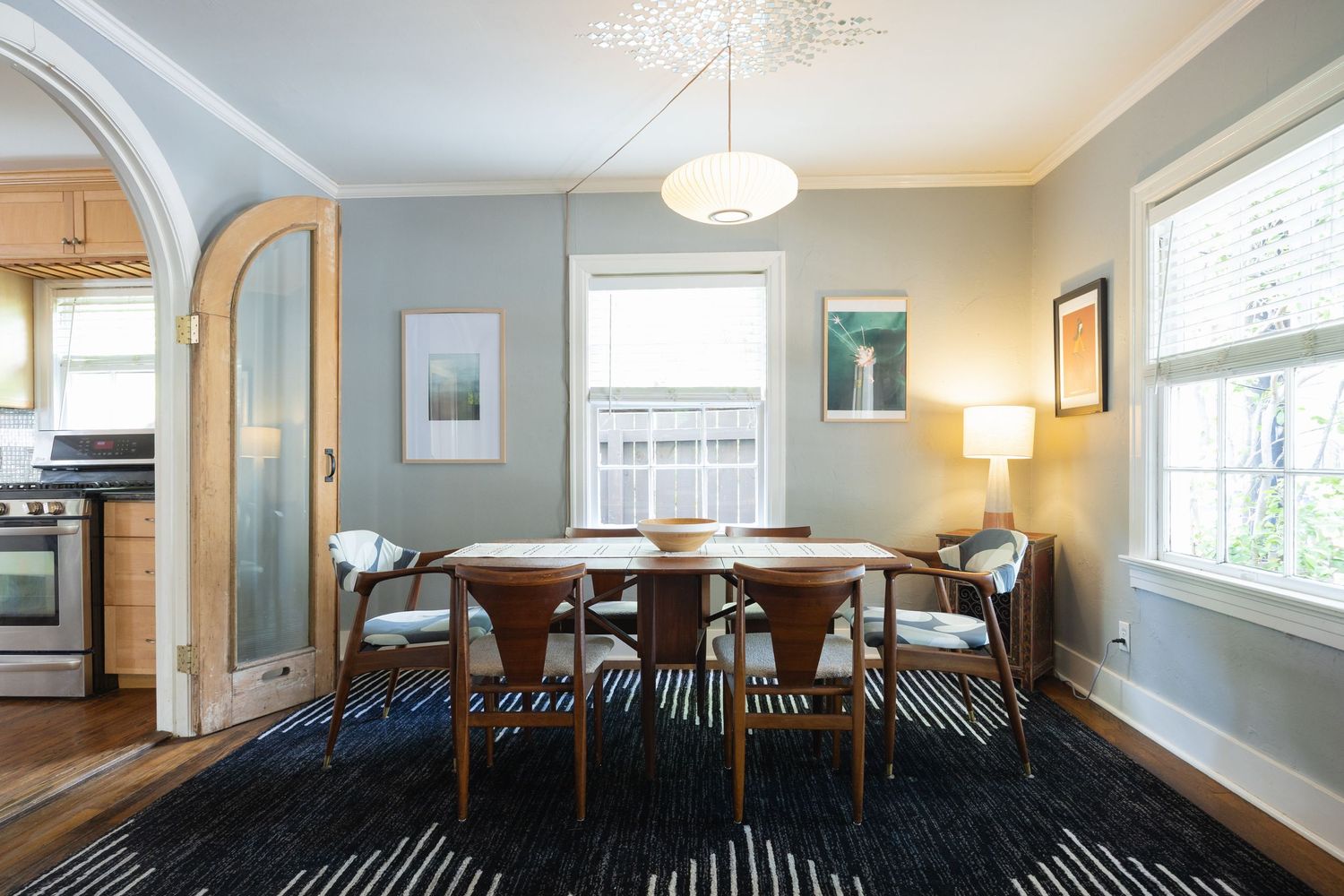 Elegant dining room with curved archway, pendant lighting, and large windows for natural light.