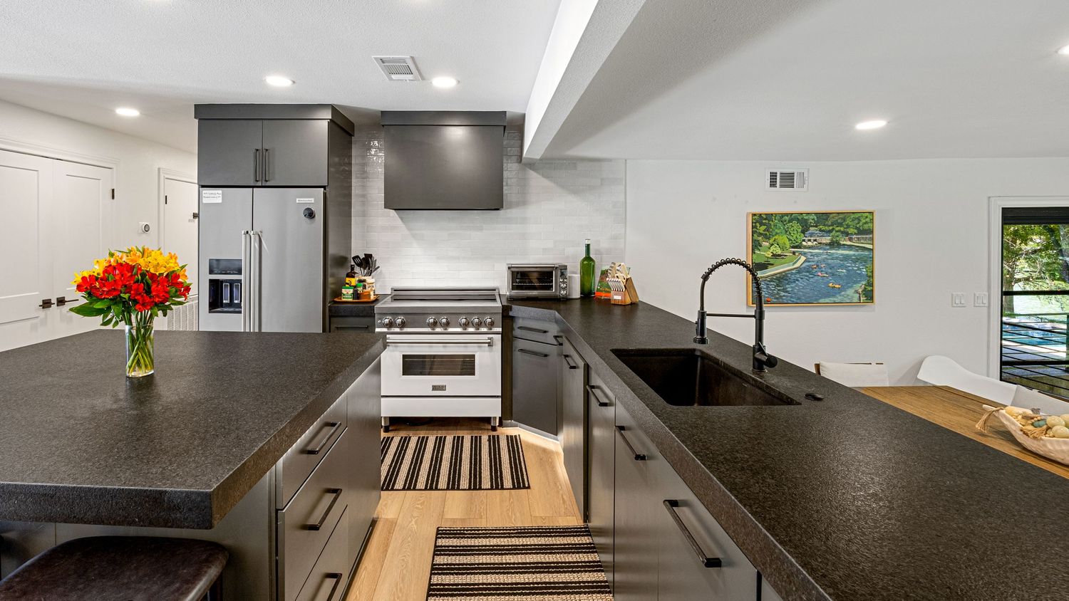 Sleek dark kitchen featuring granite countertops, stainless steel appliances, subway tile backsplash, and undermount sink.