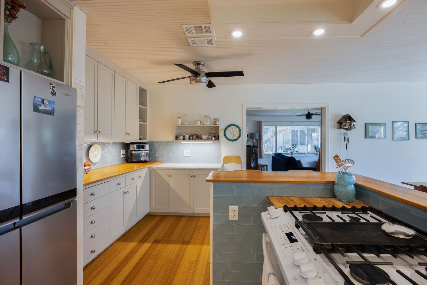Bright kitchen interior with wooden countertops and white shaker cabinets.