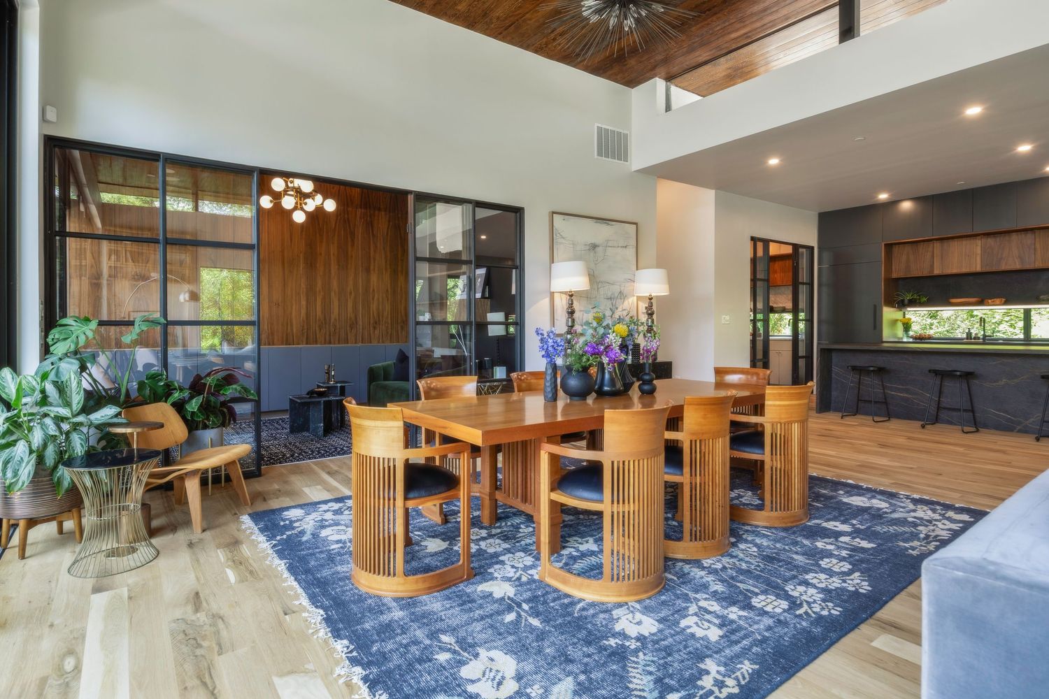 Open concept living space with blue carpet, wooden ceiling beams, and modern furniture.