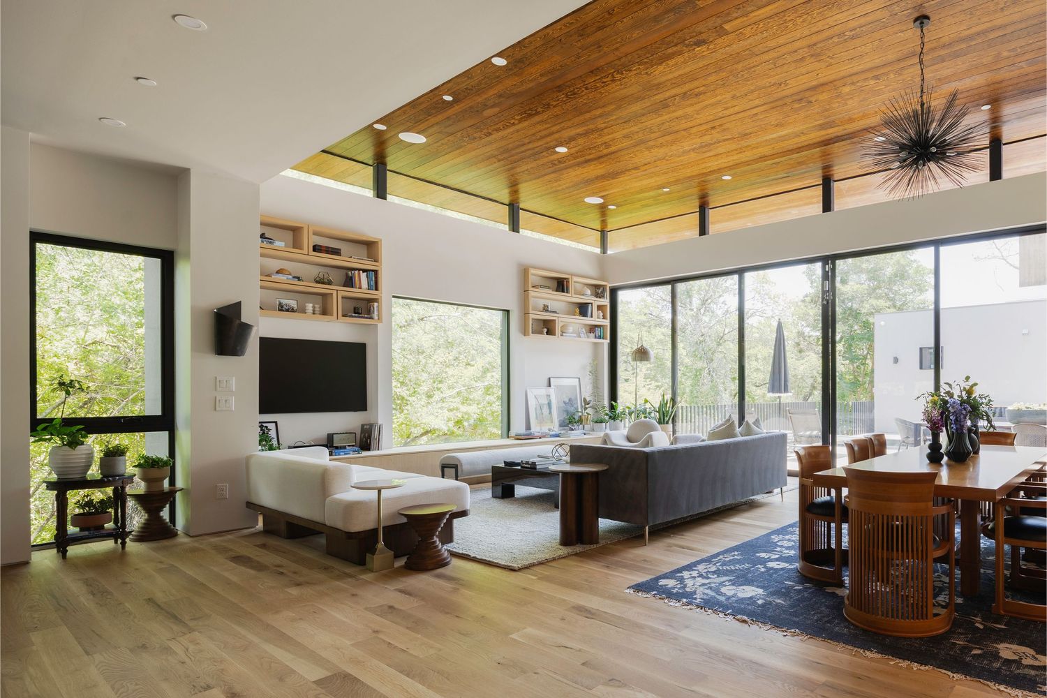 Open concept living area with wood ceiling, large windows, and modern furnishings.