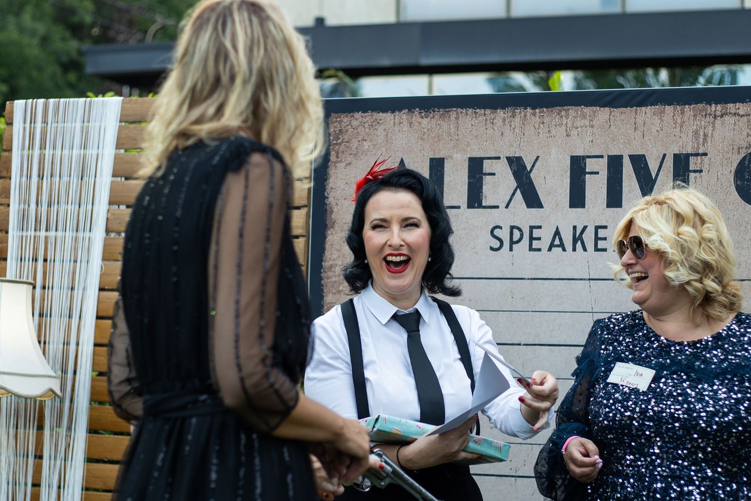 Three women laughing and networking at an Alex Five Speakers event outdoors.