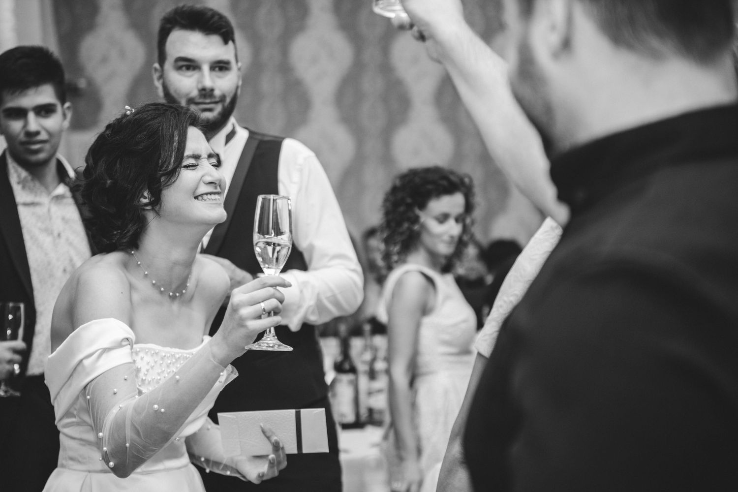 Bride and groom toasting with champagne glasses at elegant wedding reception in black and white photo.