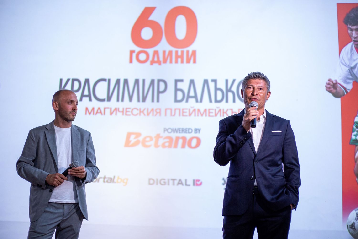 Two men on stage at Krasimir Balakov 60th anniversary celebration event with Betano sponsorship backdrop.
