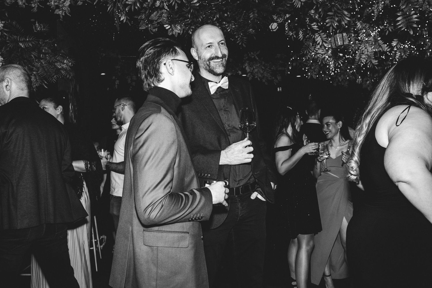 Black and white photo of two men conversing at an elegant formal evening reception.