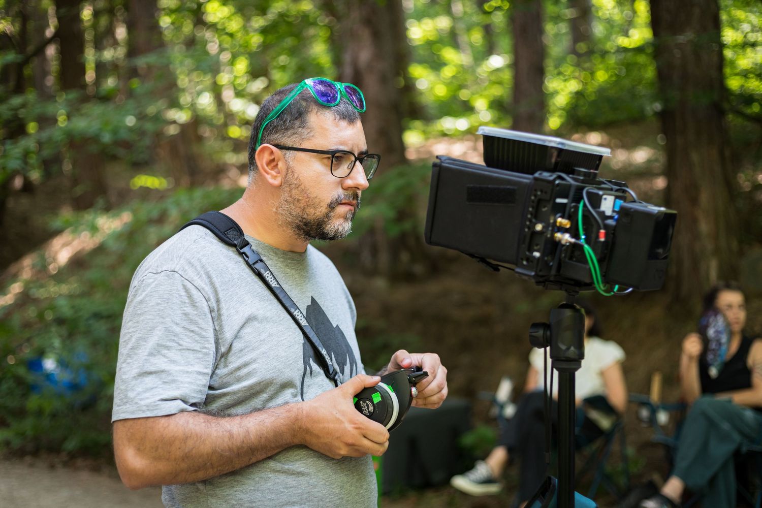 Male filmmaker operates a professional camera on a gimbal in an outdoor forest setting.