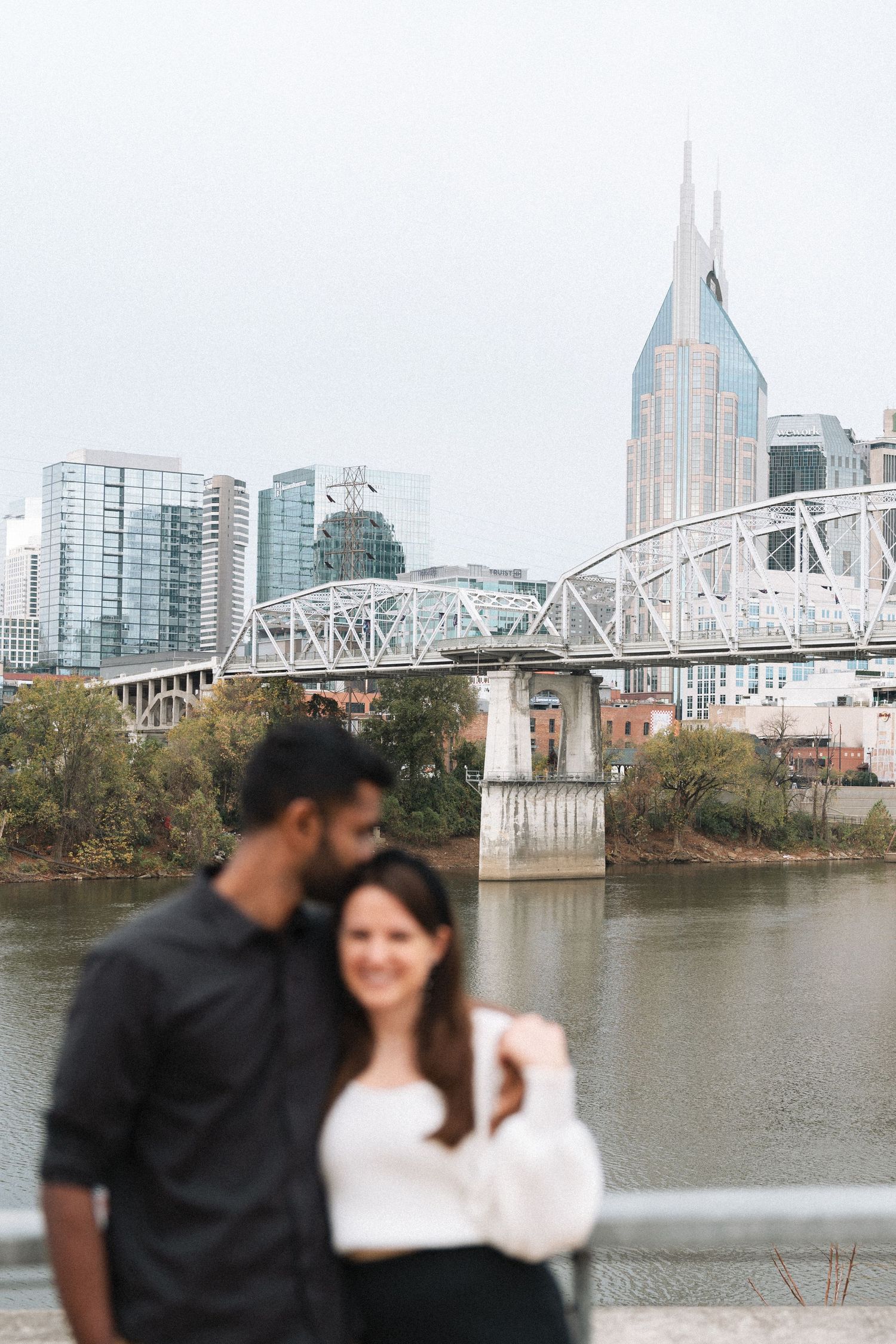 A romantic view of Nashville's skyline and riverfront with the pedestrian bridge and modern buildings in the background.